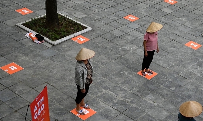 Người dân giữ khoảng cách 2m khi xếp hàng tại điểm phát gạo miễn phí ở Hà Nội ngày 11/4. Ảnh: AFP.